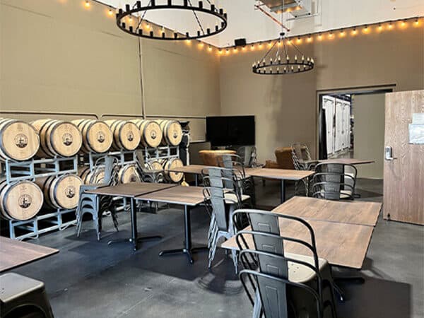 Tasting room seating beside stacked wine barrels