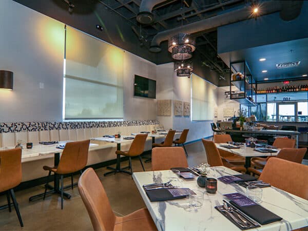 Finished restaurant dining room with tables, banquette seating, and accent lighting