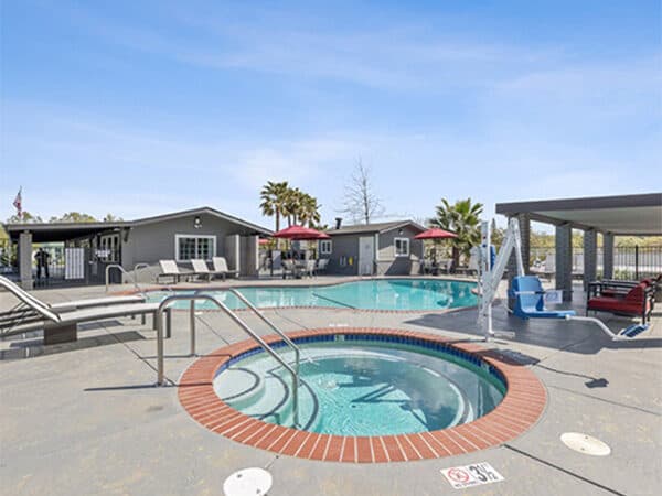 HOA pool amenity surrounded by clubhouse buildings and shaded seating